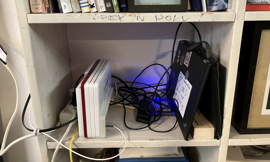 Old black Lenovo latop on a messy shelf